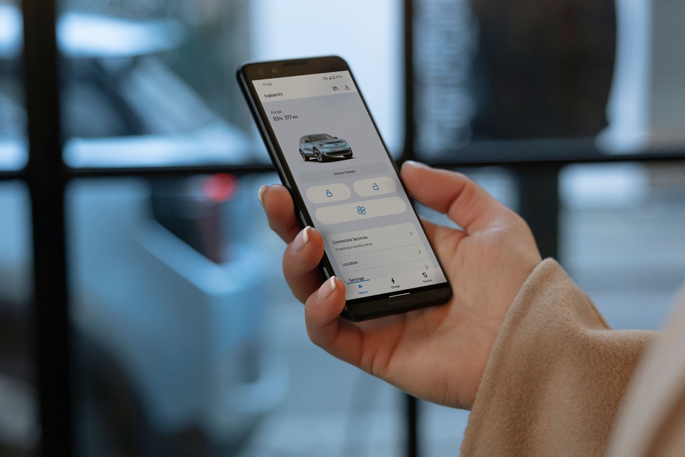A close up of a hand holding a smartphone and interacting with the Ford app