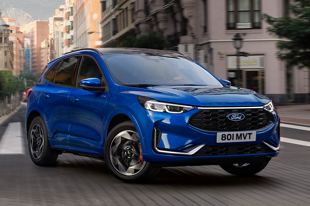 Vue avant d'un Ford Kuga bleu roulant dans une rue de la ville.