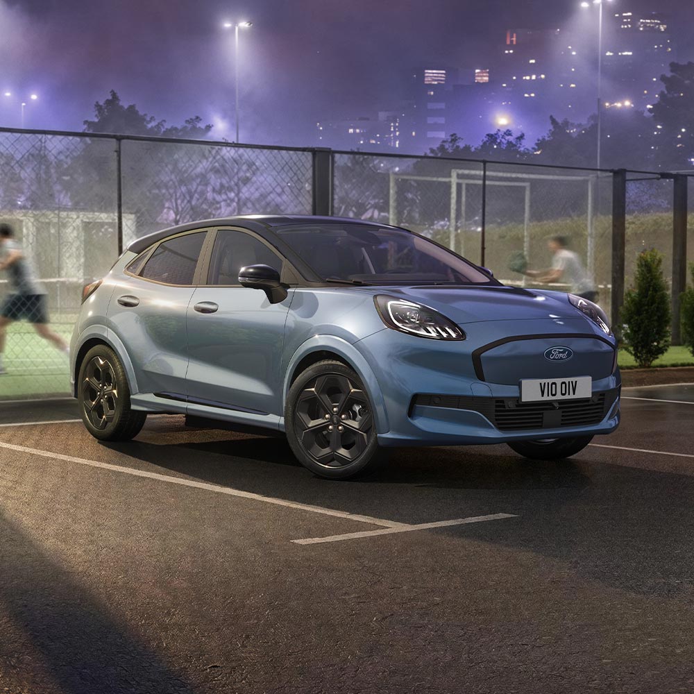 Un Ford Puma Gen-E en édition limitée Vapour Blue avec la technologie BlueCruise stationné à côté d’un terrain de padel extérieur.