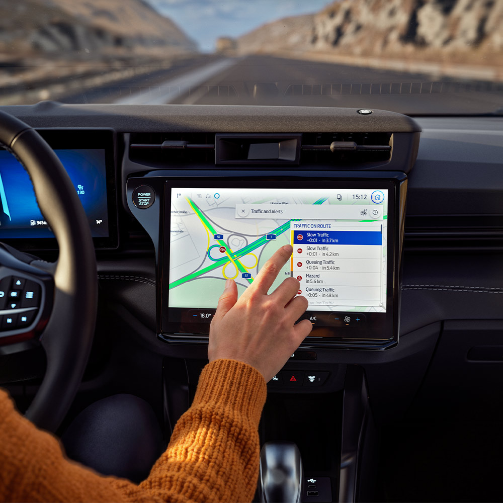 Un conducteur utilisant la fonctionnalité de navigation connectée sur l’écran numérique d’un Ford Puma BlueCruise Edition.