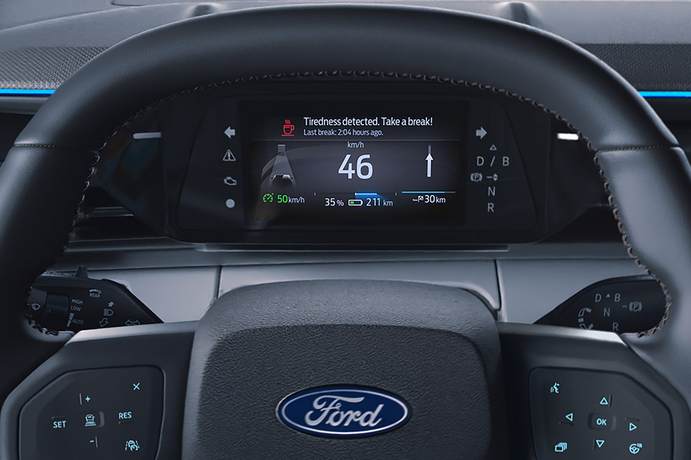 Le tableau de bord numérique derrière le volant du Ford Explorer, affichant la fonction d'alerte du conducteur.