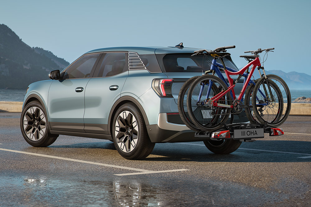 Ford Explorer bleu clair avec deux vélos sur le porte-bagages de toit, roulant sur une route de montagne.