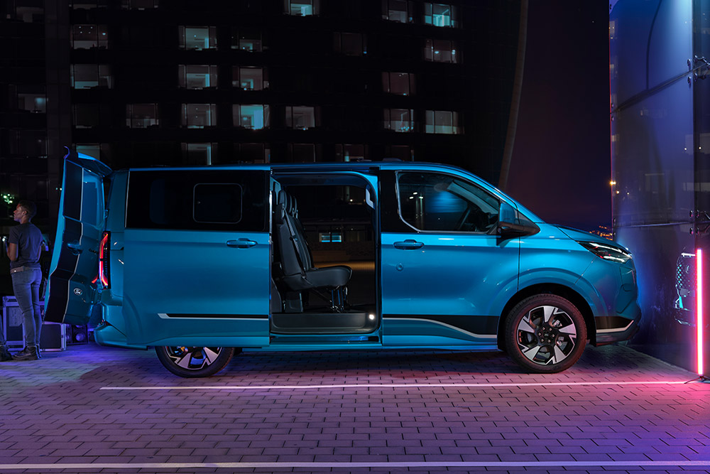 Un livreur décharge des colis d'un Ford Transit Custom rouge.