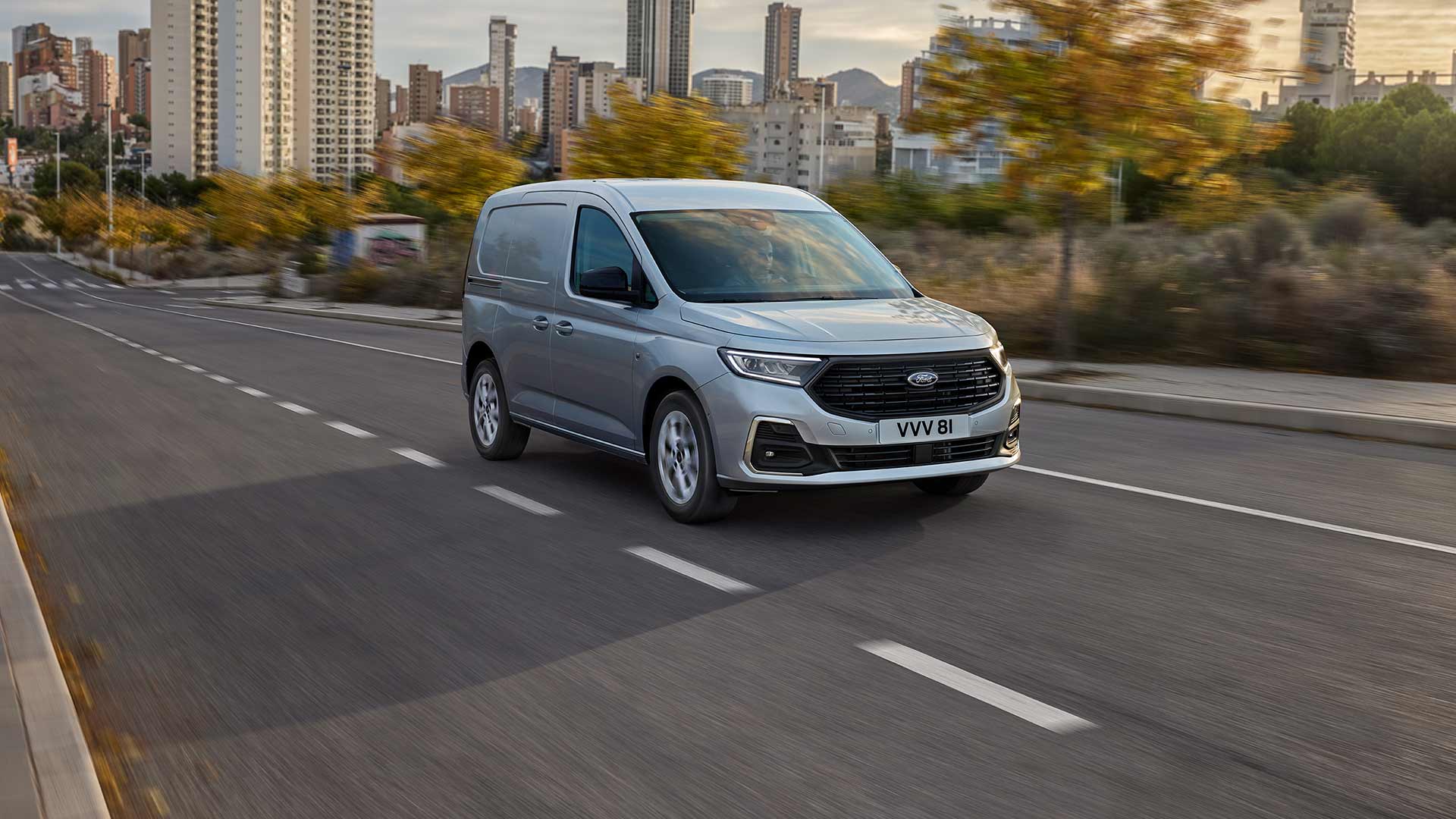 Ford Transit Connect circulant en ville, mettant en avant les entourages de feux antibrouillard extérieurs chromés et les phares automatiques.