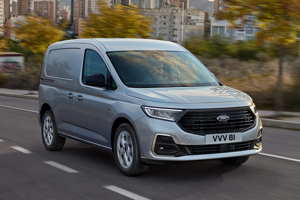 Ford Transit Connect circulant en ville, mettant en avant les entourages de feux antibrouillard extérieurs chromés et les phares automatiques.