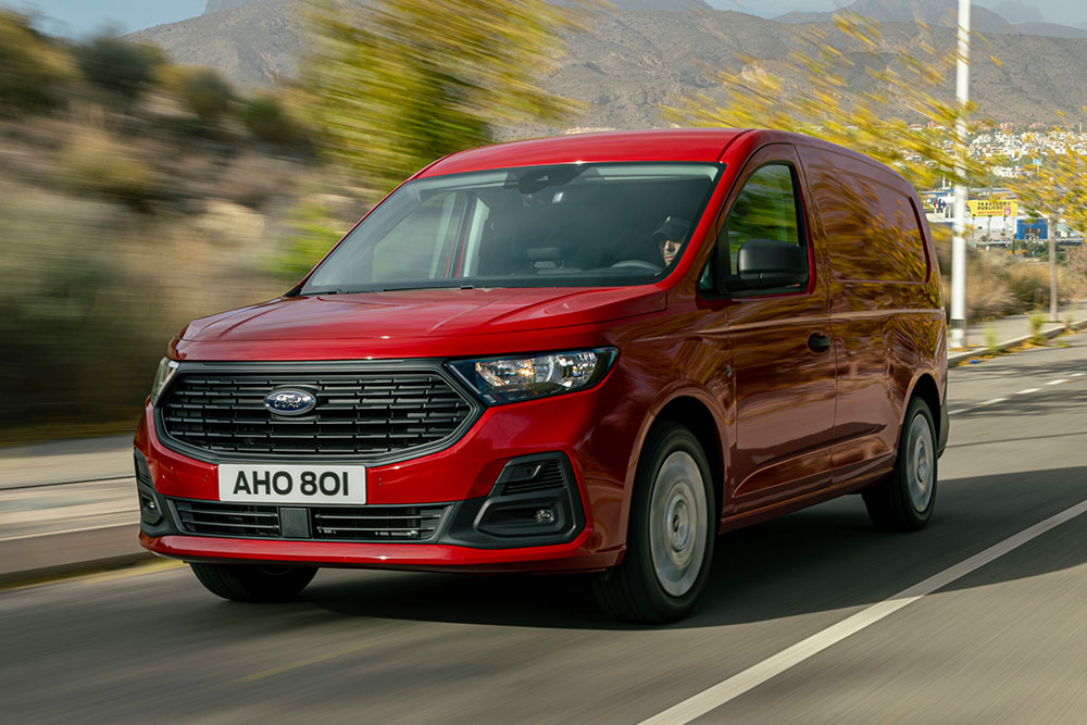 Ford Transit Connect circulant sur route, mettant en avant la calandre avant et les phares automatiques.