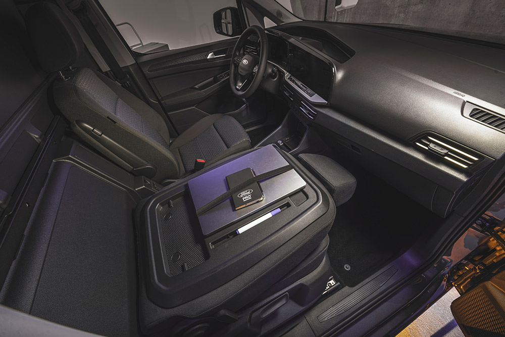 Intérieur du Ford Transit Connect, montrant le tableau de bord, les sièges, un ordinateur portable et un téléphone sur la console centrale.