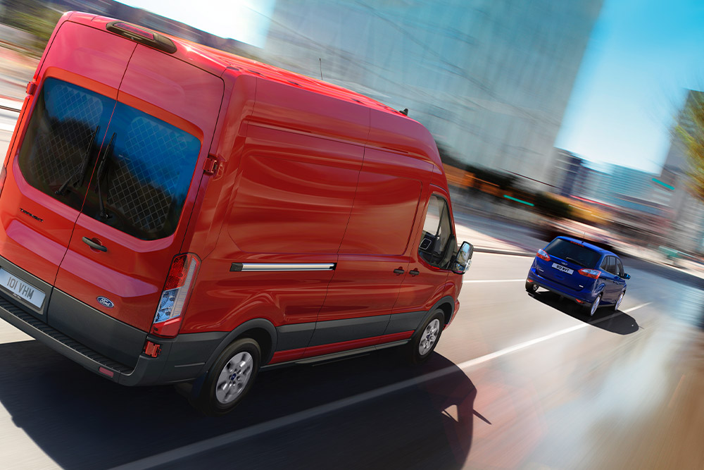 Fourgon Ford Transit rouge roulant sur une route.