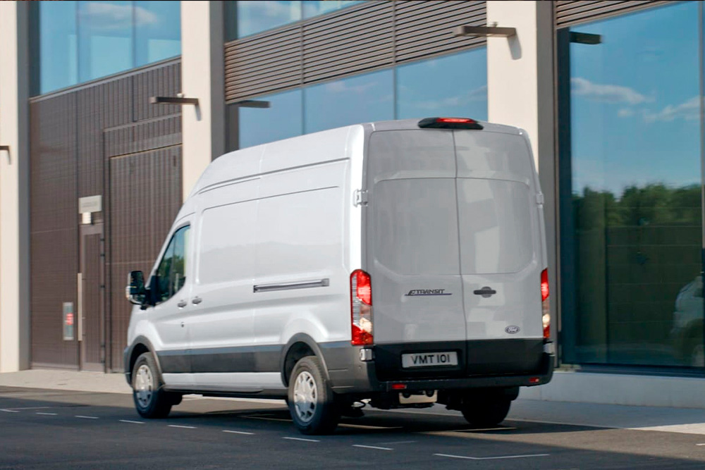 Vue arrière d’un fourgon Ford Transit argenté stationné en ville. 