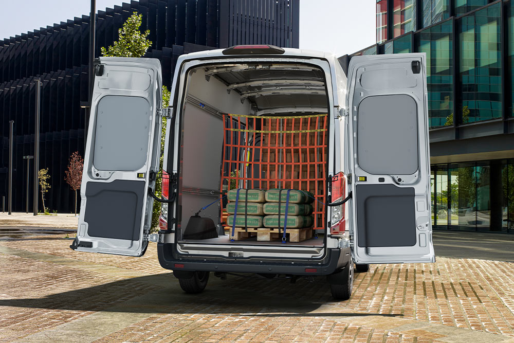 Fourgon Ford Transit avec portes arrière ouvertes, chargement à l’intérieur.