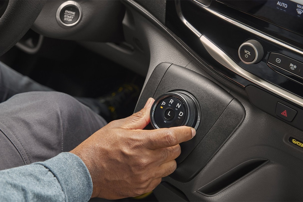 Main actionnant le sélecteur rotatif de vitesses sur la console centrale d’un fourgon Ford Transit châssis-cabine.