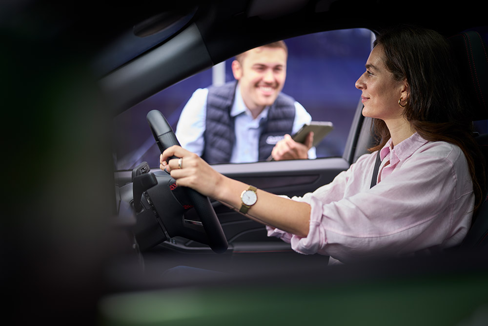 Personne au volant d’une Ford regardant un technicien tenant une tablette à l’extérieur.